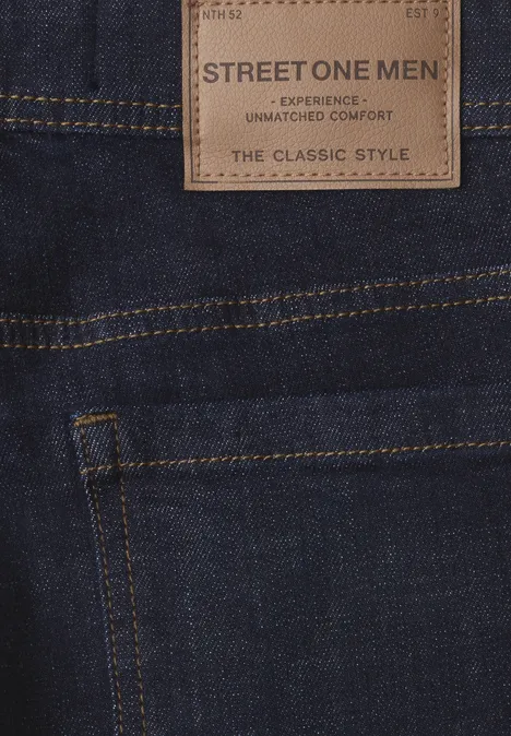 Donkere herenjeans, close-up van de zak en het leren label 'STREET ONE MEN THE CLASSIC STYLE'.