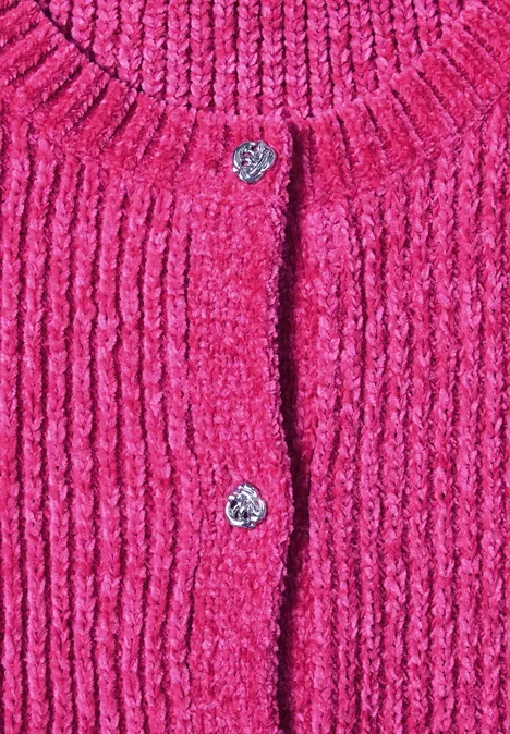 Nahaufnahme eines leuchtend pinken, grob gestrickten Cardigans mit silbernen Blumenknöpfen.