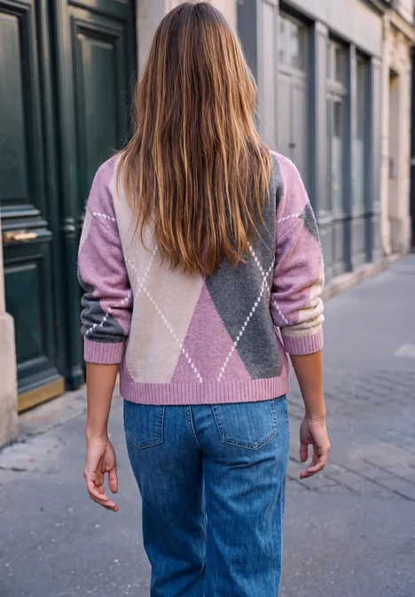 Une femme aux cheveux longs porte un pull à motifs et un jean en se promenant en ville.