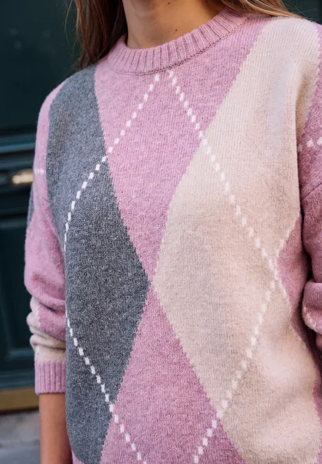 Femme portant un pull à losanges rose, gris et crème