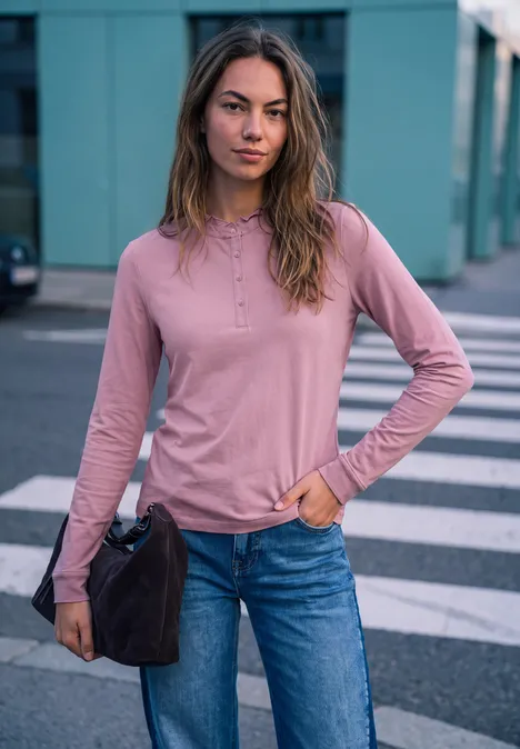 Shirt met lange mouwen, ronde hals en ruches pearly rose Junge Frau in rosa Langarmshirt und Jeans steht lässig auf dem Zebrastreifen, hält eine Tasche.