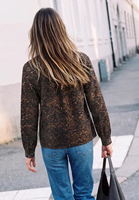 Tunique à col fendu et détails rivetés charred brown Femme vue de dos en jean et cardigan à motifs, marchant sur un trottoir avec un sac à main