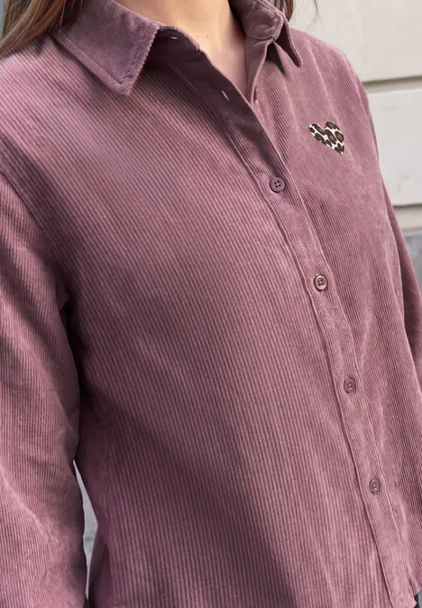 Hemdbluse aus Cord mit Herzdetail hazy rose Eine Person trägt ein altrosa Cordhemd mit Knöpfen und einem kleinen Aufnäher an der Brust.