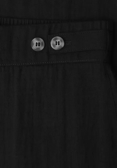 Schwarzes Stoffdetail mit zwei runden Knöpfen an einem schmalen Riegel.