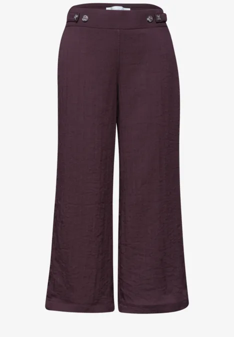 Dunkelviolette, weit geschnittene Damenhose mit hohem Bund und Knopfdetails.