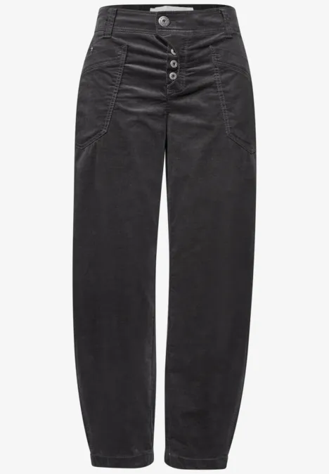 Jean en velours côtelé noir taille haute, boutonnière frontale, plis discrets et coupe droite ample.