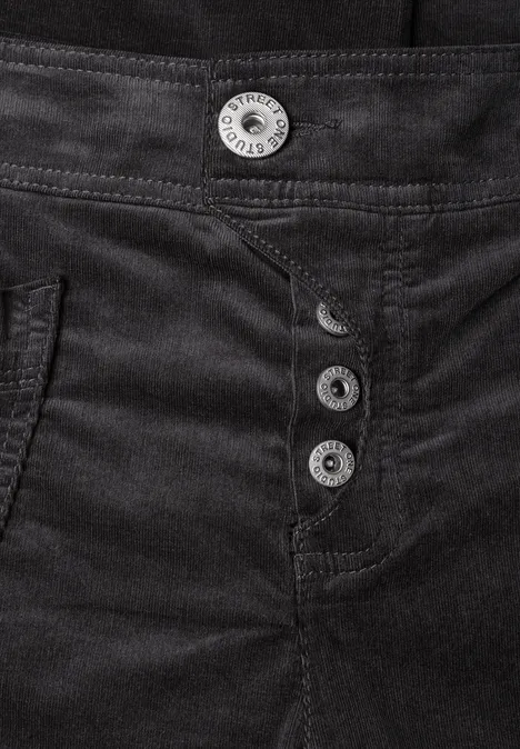 Plan rapproché d’un pantalon noir en tissu épais, orné de quatre boutons argentés à la taille.