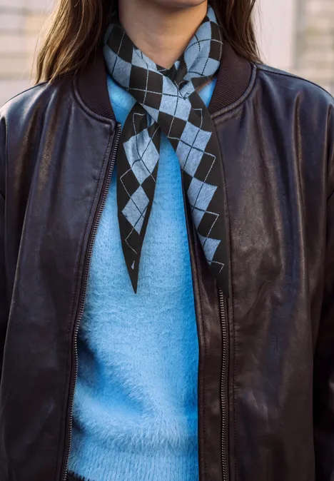Schwarze Lederjacke über hellblauem Pullover, diamond-muster Halstuch in Schwarz und Hellblau.