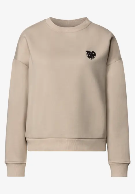 Sweat-shirt beige épuré à col rond, petit emblème cœur noir sur la poitrine.