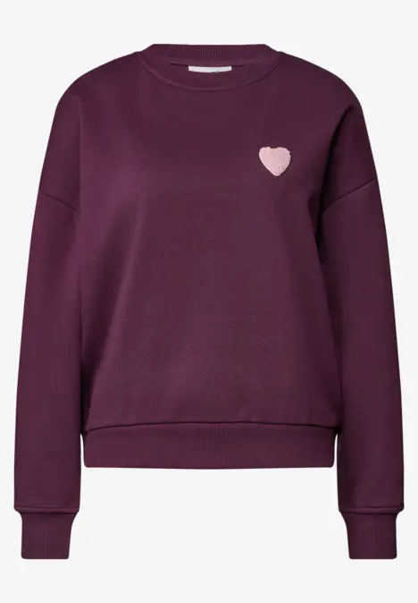 Pull violet foncé à manches longues, bords-côtes et petit cœur rose sur la poitrine.