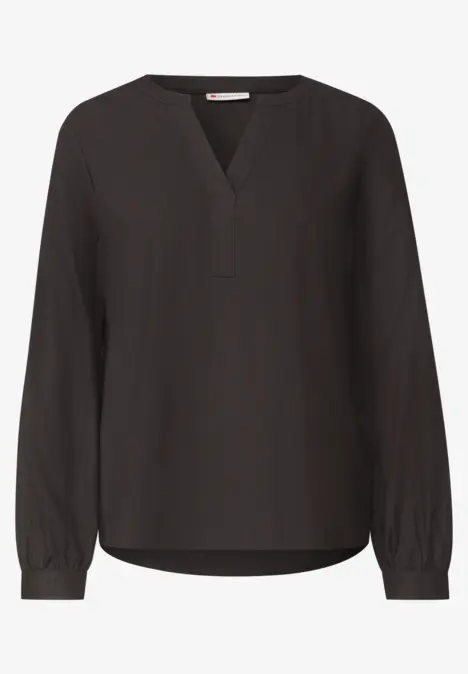 Zwarte, losvallende blouse met V-hals en lange mouwen.