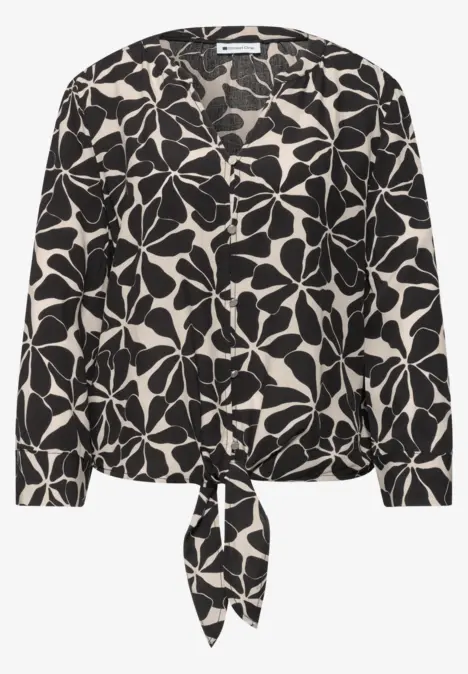 Blouse noire et blanche à motif floral oversize avec nœud à la taille.