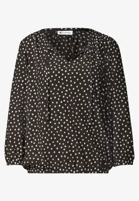 Blouse noire à motif de petits coeurs blancs, col en V et manches longues.