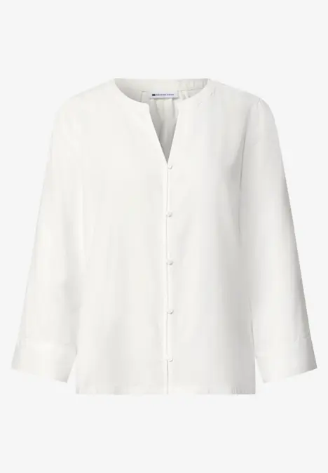 Chemisier blanc à manches longues, col rond et patte de boutonnage, sobre et élégant.