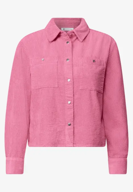 Veste-chemise rose en velours côtelé avec col chemise, poches poitrine et boutons-pression argentés.