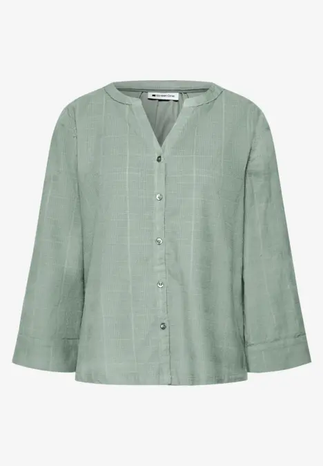 Losvallende lichtgroene blouse met V-hals, knoopsluiting en wijde mouwen.