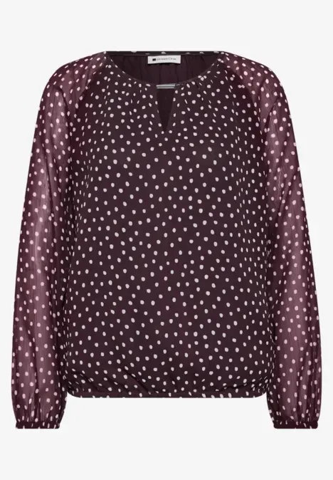Blouse bordeaux à pois blancs, manches longues, encolure en V et taille élastiquée.