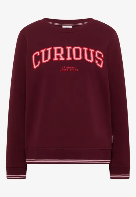 Bordeauxfarbenes Sweatshirt mit weißem Schriftzug 'CURIOUS' und dezenten Streifen an Bündchen und Saum.