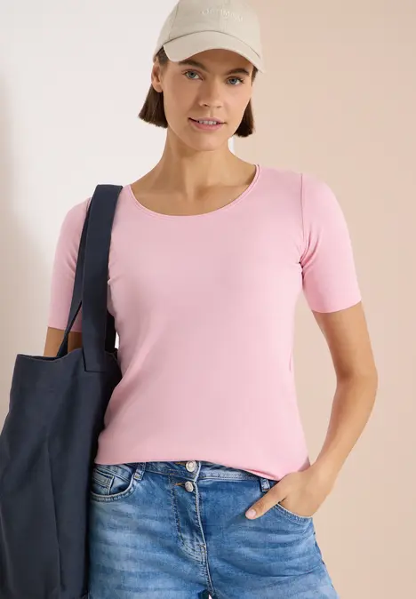 Vrouw met roze shirt, blauwe jeans en donkergekleurde tas