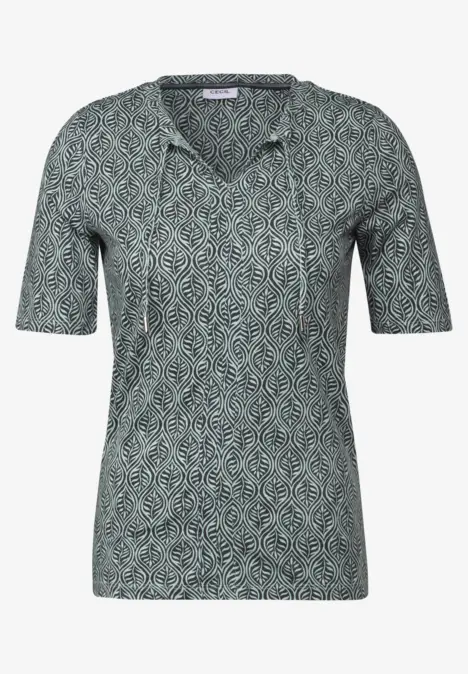 Grünes Shirt mit kurzem Arm und Blattmuster.