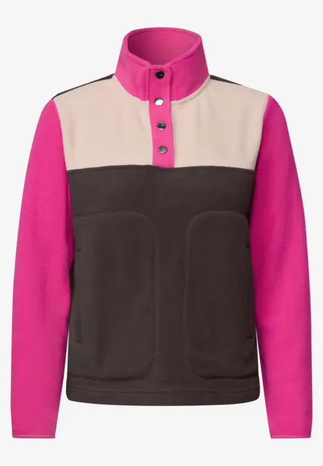 Veste polaire à col montant, patte de boutonnage, manches fuchsia, empiècement beige et corps marron foncé.