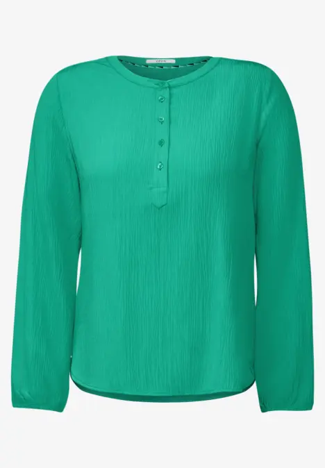 Grüne Bluse mit langen Ärmeln und Knopfleiste.