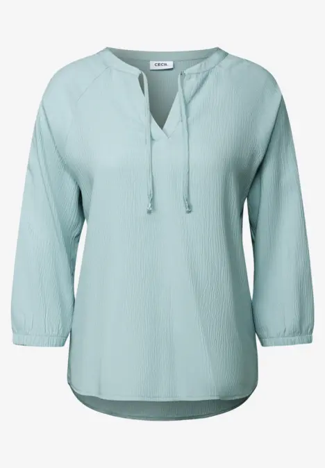 Hellblaue Bluse mit langen Ärmeln und Bändchen am Ausschnitt.