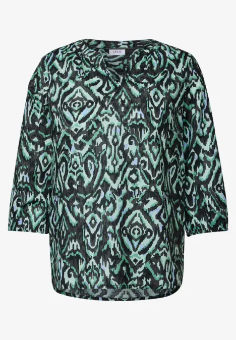 Bluse mit grün-schwarzem abstraktem Muster und langen Ärmeln.
