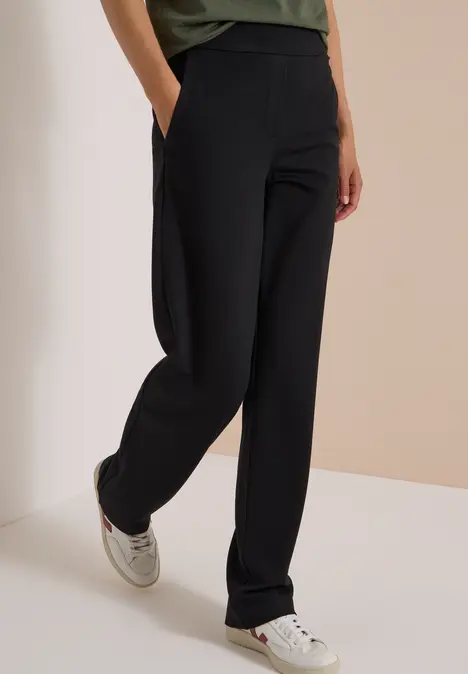 Schwarze, gerade geschnittene Hose mit Taschen, kombiniert mit weißen Sneakern.