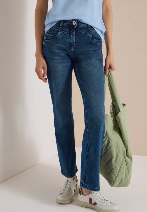 Dunkelblaue Straight-Leg-Jeans, weiße Sneakers und grüne gesteppte Tragetasche.
