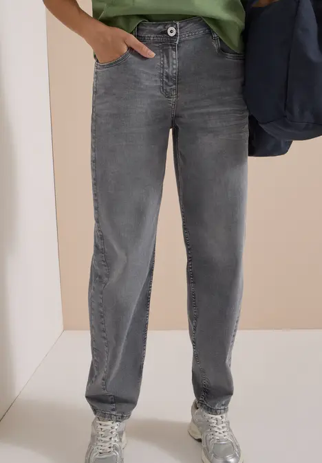 Gerade geschnittene graue Jeans mit Knopfverschluss, kombiniert mit weißen Sneakers.