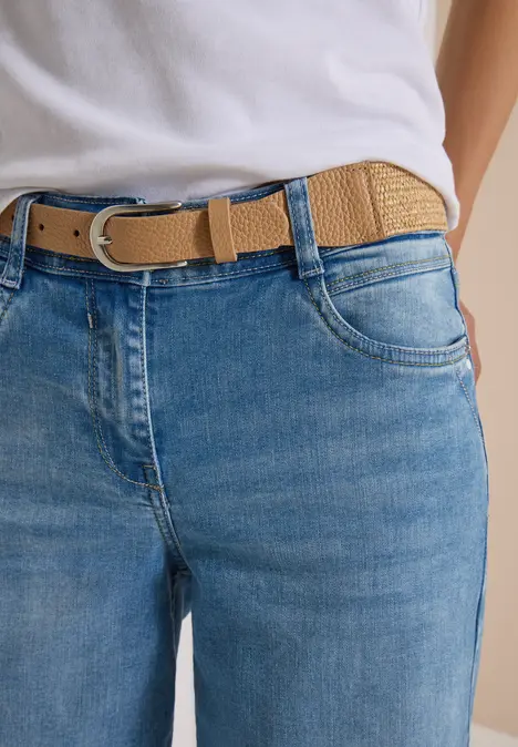 Nahaufnahme einer Jeanshose mit hellbraunem geflochtenem Gürtel, lockerer Sitz an der Taille.