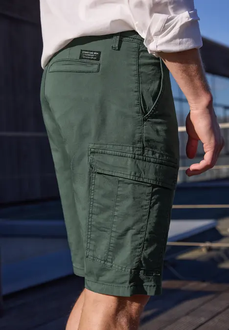 Nahaufnahme eines Mannes in grünen Cargo-Shorts mit Taschen, weiße Hemdärmel sichtbar.