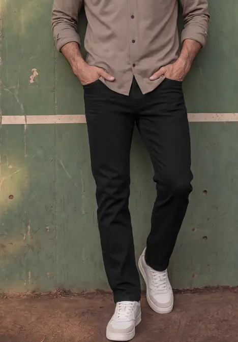 Unterkörper eines Mannes vor grüner Wand, er trägt schwarze Jeans und weiße Sneaker.