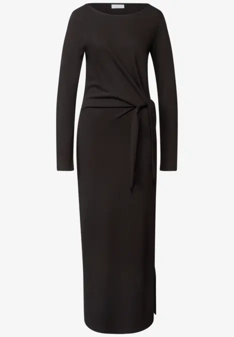 Robe mi-longue noire à manches longues, taille marquée par un noeud latéral, coupe ajustée.